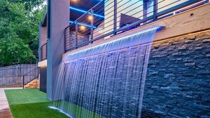 A modern outdoor water feature with a stone wall and wooden deck. - Discover Lakeside Bliss on Lake Hamilton (Hot Springs)