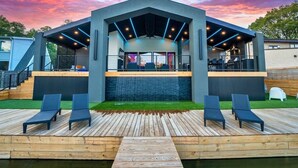A modern outdoor lounge area with a pool, wooden deck, and lounge chairs. - Discover Lakeside Bliss on Lake Hamilton (Hot Springs)