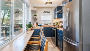 Una cocina moderna con un refrigerador de acero inoxidable, armarios azul oscuro y un banco de madera.
