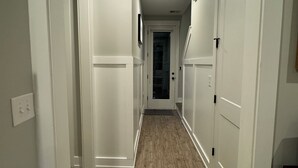 Un pasillo con paredes blancas, suelo de madera y puertas cerradas.