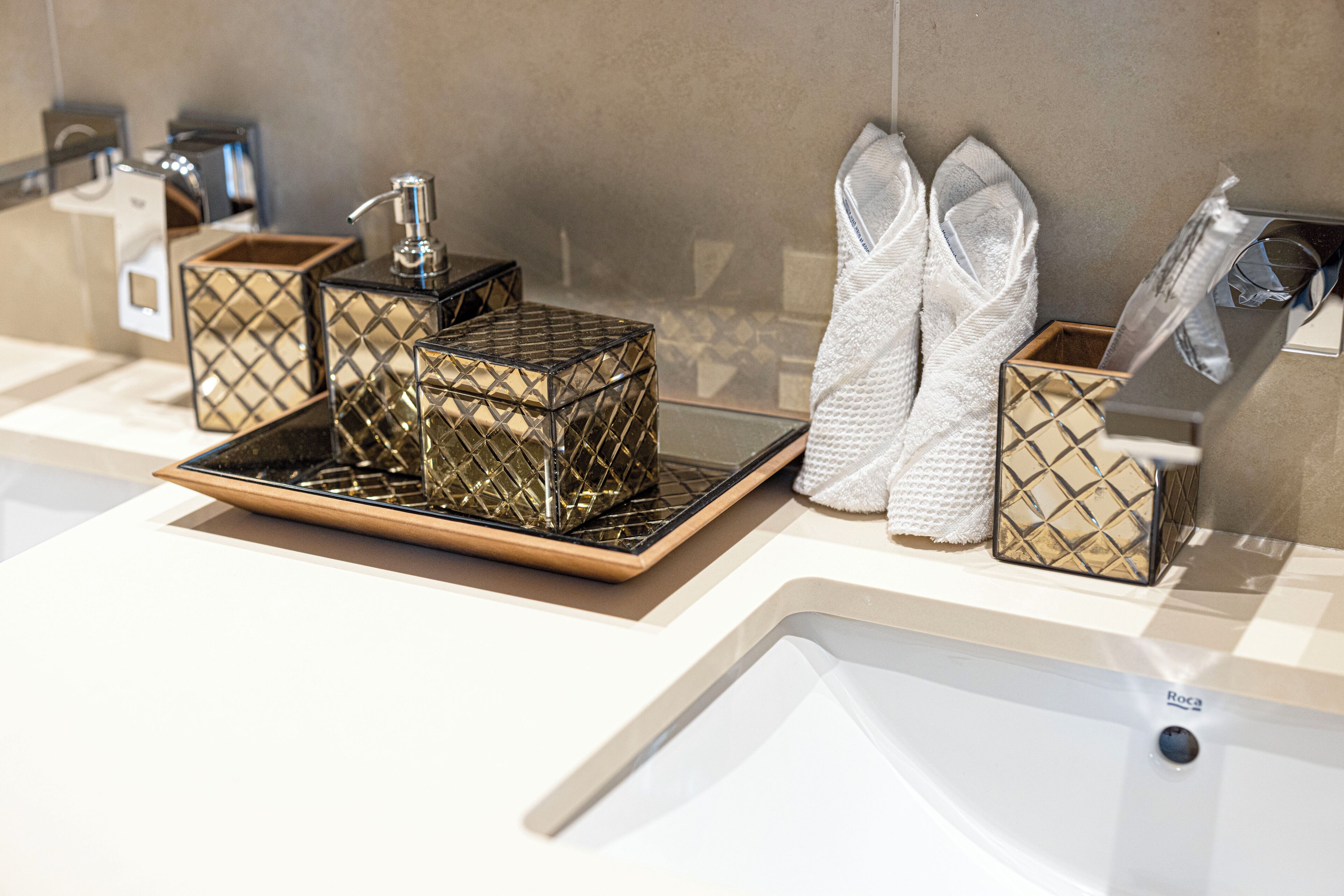 Une salle de bain au design moderne, comprenant un lavabo, un miroir et un porte-serviettes avec des serviettes soigneusement pliées.
