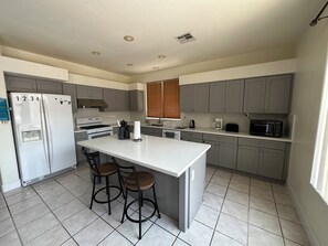 Enjoy cooking and dining in this well-equipped kitchen with a central island, refrigerator, stove, microwave, and coffee maker.