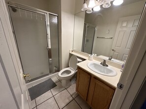Bathroom features a glass-enclosed shower stall, toilet, and sink with a mirror.