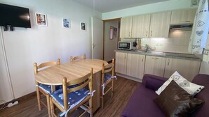 Un espacio habitable compacto con una mesa de comedor, sillas, un sofá, una kitchenette y un televisor.