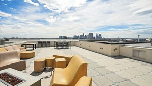 Een terras op het dak met zitplaatsen en uitzicht op de skyline van de stad.