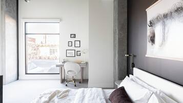Ein modernes Schlafzimmer mit einem großen Bett, einem Schreibtisch und Blick auf die Stadt.