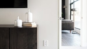 Un salon moderne avec un meuble en bois foncé, un téléviseur à écran plat et une grande fenêtre donnant sur l’extérieur.