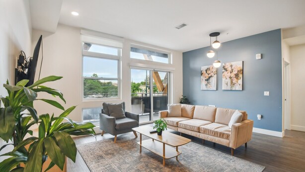 Un salon moderne avec un canapé, un fauteuil, une table basse et de grandes fenêtres.