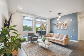 A modern living room with a sofa, armchair, coffee table, and large windows. - Sleek & Chic Vibes | Spacious 2BR LoHi Loft | Rooftop (Denver)