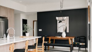 A modern kitchen with a white countertop, wooden chairs, and a black dining table. - Rhythm of Night | 2BR LoHi Loft w/ Balcony (Denver)