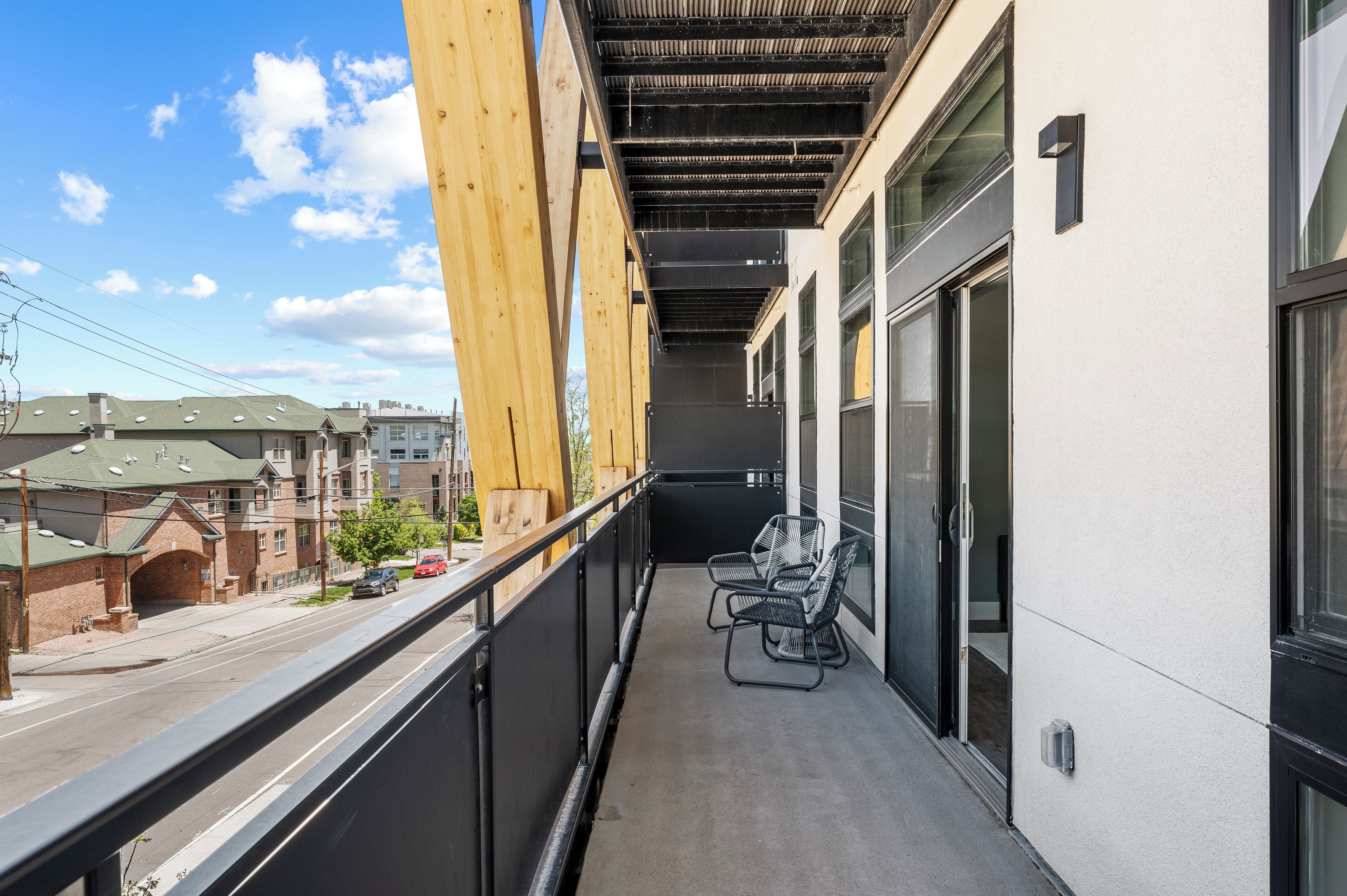 Ein Balkon mit Blick auf eine Straße, einem Holzbalkenbau und zwei Stühlen.