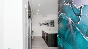 Een moderne keuken met een marmeren spatwand, roestvrijstalen apparatuur en een centraal eiland met een spoelbak.