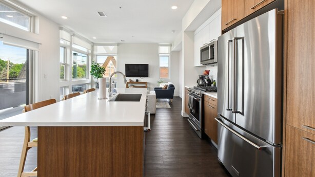 A modern kitchen with a large island, stainless steel appliances, and wooden cabinets. - Rose All Day | 2BR LoHi Loft | Walk to Ball Arena | Dog-Friendly (Denver)