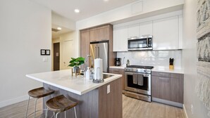 Una cocina moderna con una isla central, electrodomésticos de acero inoxidable y armarios de madera.