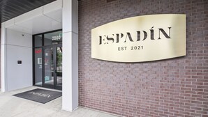 Entrada de un edificio con un letrero que dice "ESPADIN EST 2021" y una puerta identificada con "FACP".