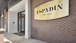 Entrada de un edificio con un letrero que dice "ESPADIN EST 2021" y una puerta de vidrio con la etiqueta "FACP".