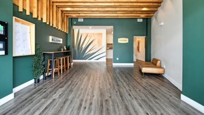 Un área de recepción con techo de madera, mostrador de recepción, sofá y planta.