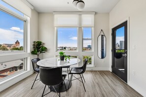 A modern room with a round table, black chairs, large windows, and a view of a cityscape.