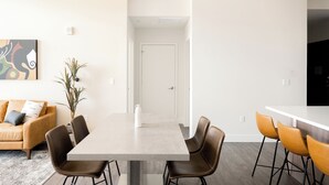Un comedor moderno con una mesa rectangular, cuatro sillas, una lámpara colgante y una planta en maceta.