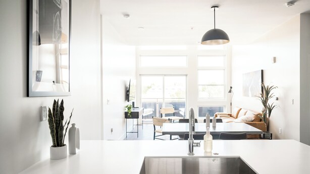 Una cocina moderna con una isla grande, pileta de acero inoxidable e iluminación colgante.