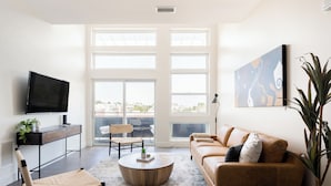 Una sala de estar moderna con un televisor grande, un sofá, una mesa de centro y una planta.