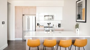 Cocina moderna con una isla central, electrodomésticos de acero inoxidable y un espacio de comedor con cuatro sillas.