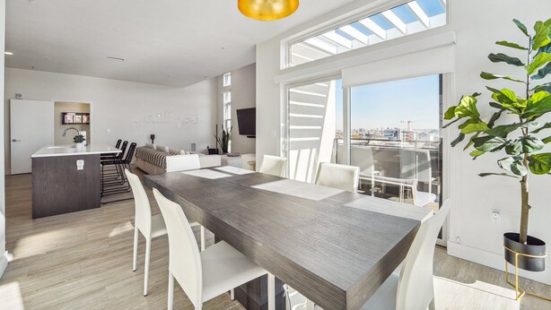 A modern kitchen with a central island, white chairs, and a dining table.