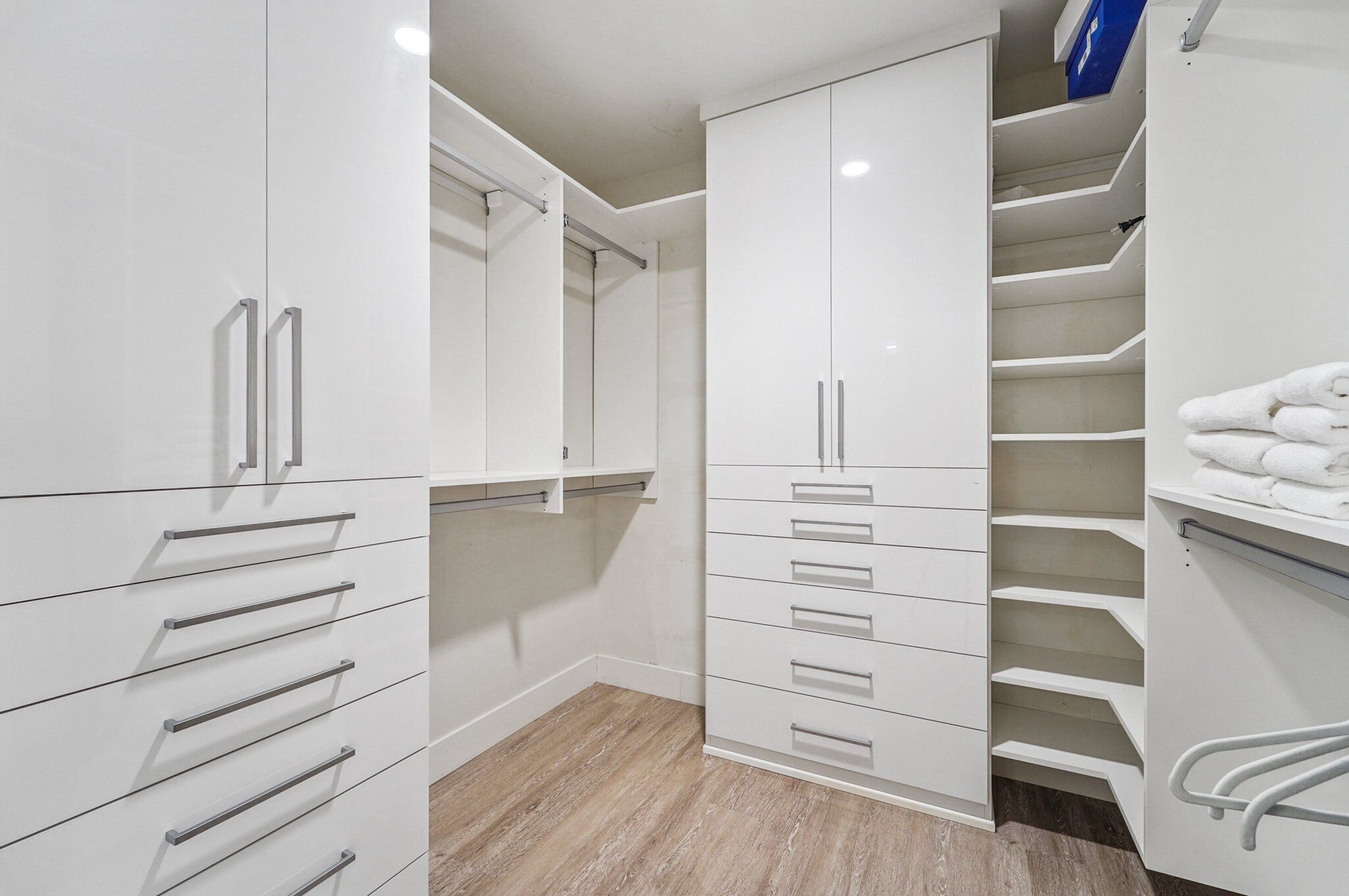 A modern closet with white cabinetry, multiple drawers, and a built-in shelf.