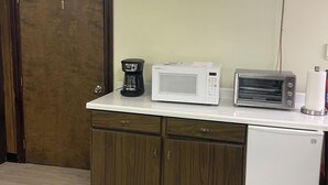 Un angolo cottura dotato di forno a microonde, tostapane, macchina del caffè e frigorifero.