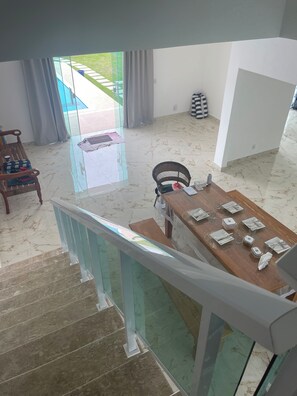 Um interior moderno com área de jantar, escada e vista para o exterior.