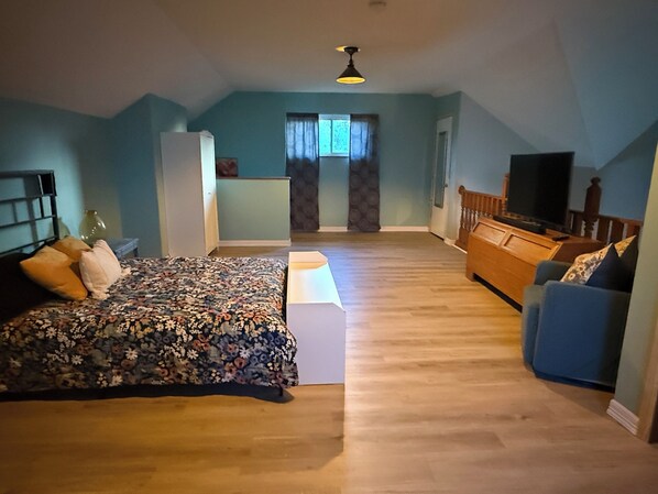 A bedroom with a bed, a television, a dresser, and a window.