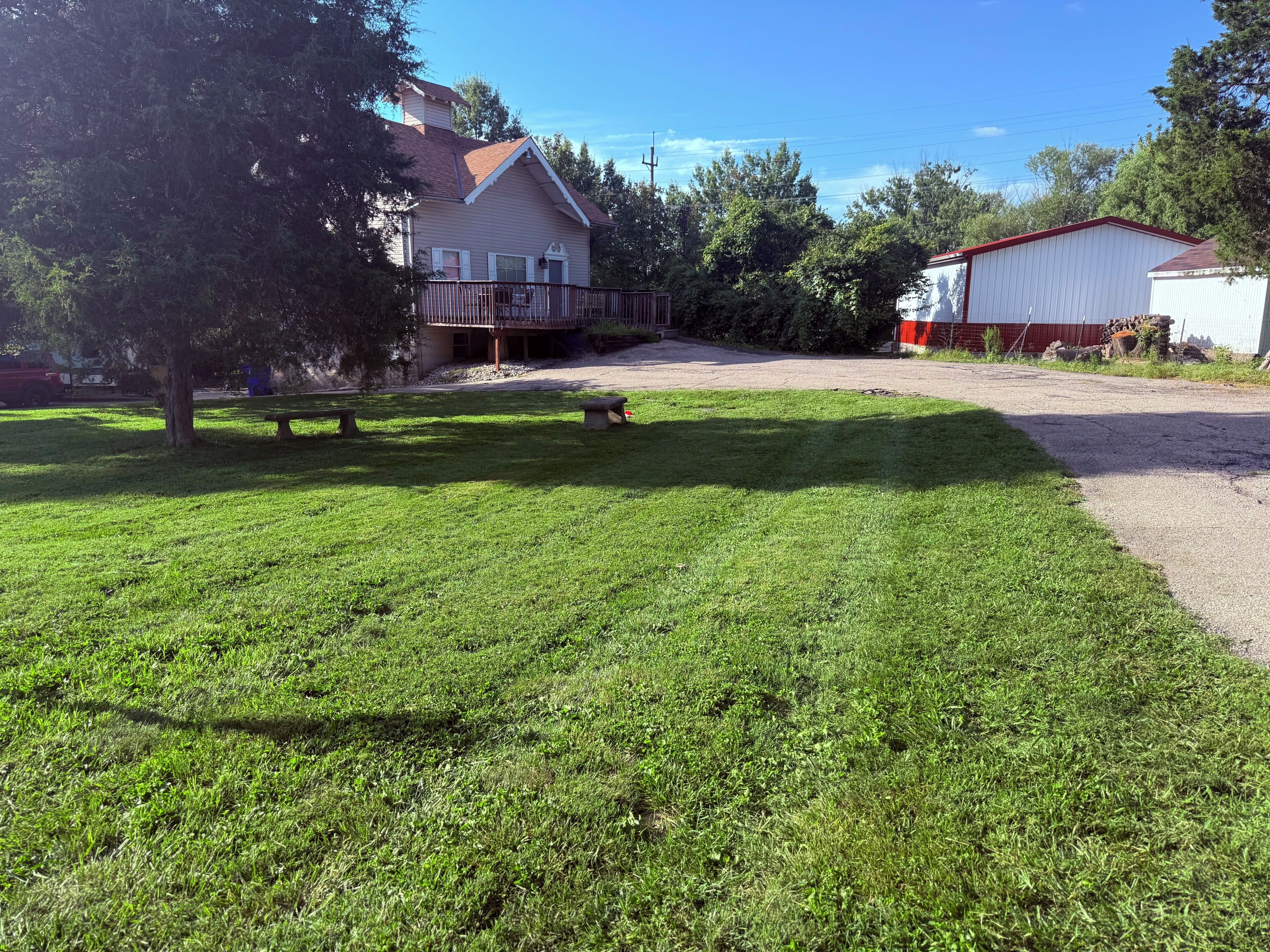 A residential property with a well-maintained lawn, a porch with outdoor seating, and a detached garage.