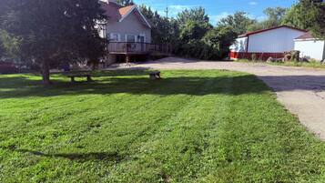 A residential property with a well-maintained lawn, a porch with outdoor seating, and a detached garage.