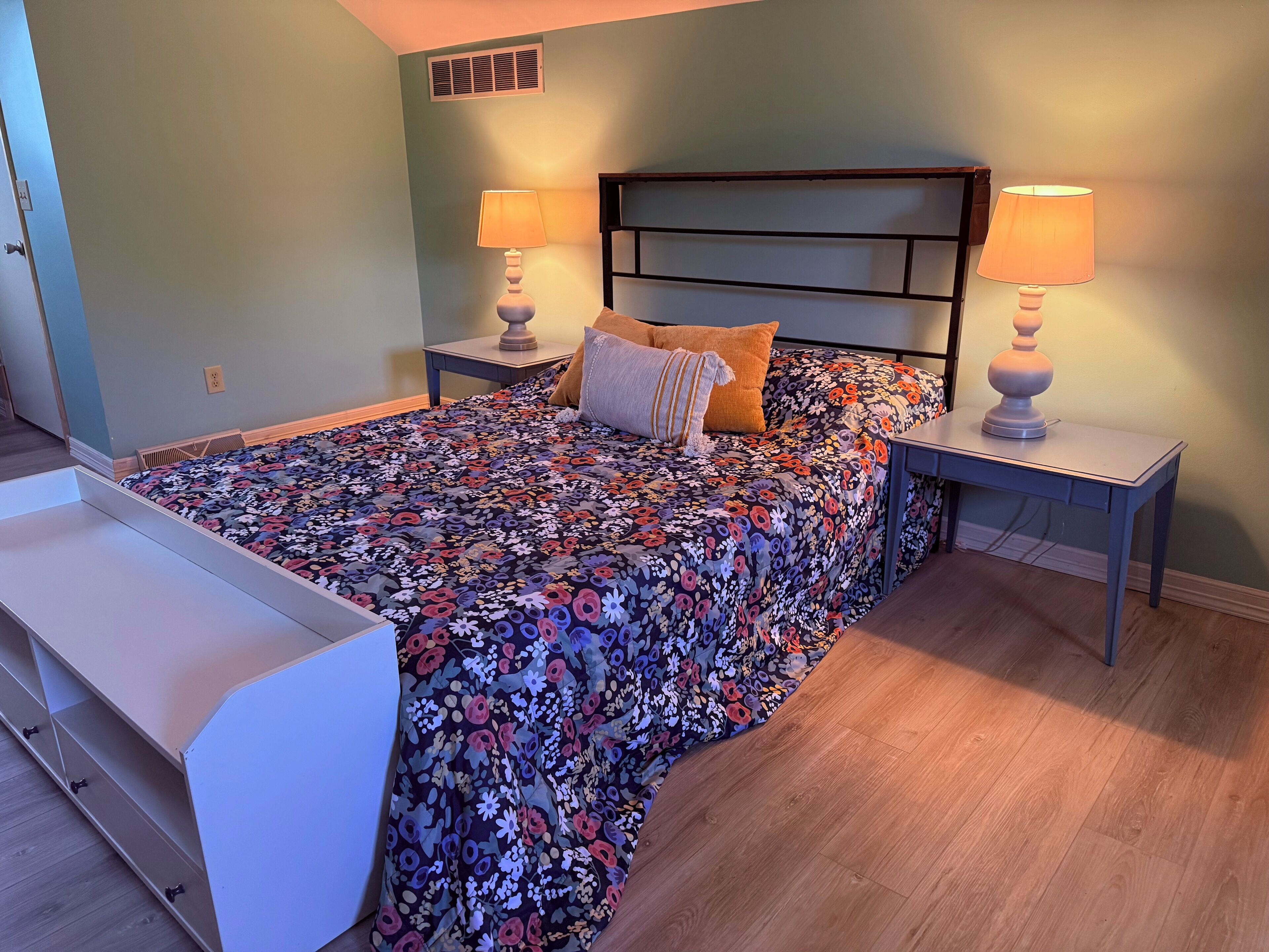 A bedroom with a bed, two nightstands, a bench, and a headboard.