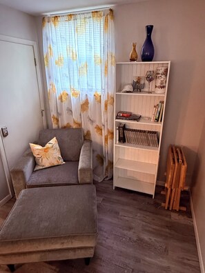 A living room with a sofa, a coffee table, a bookshelf, and a radiator. - Cozy Cottage on New London (Hamilton)