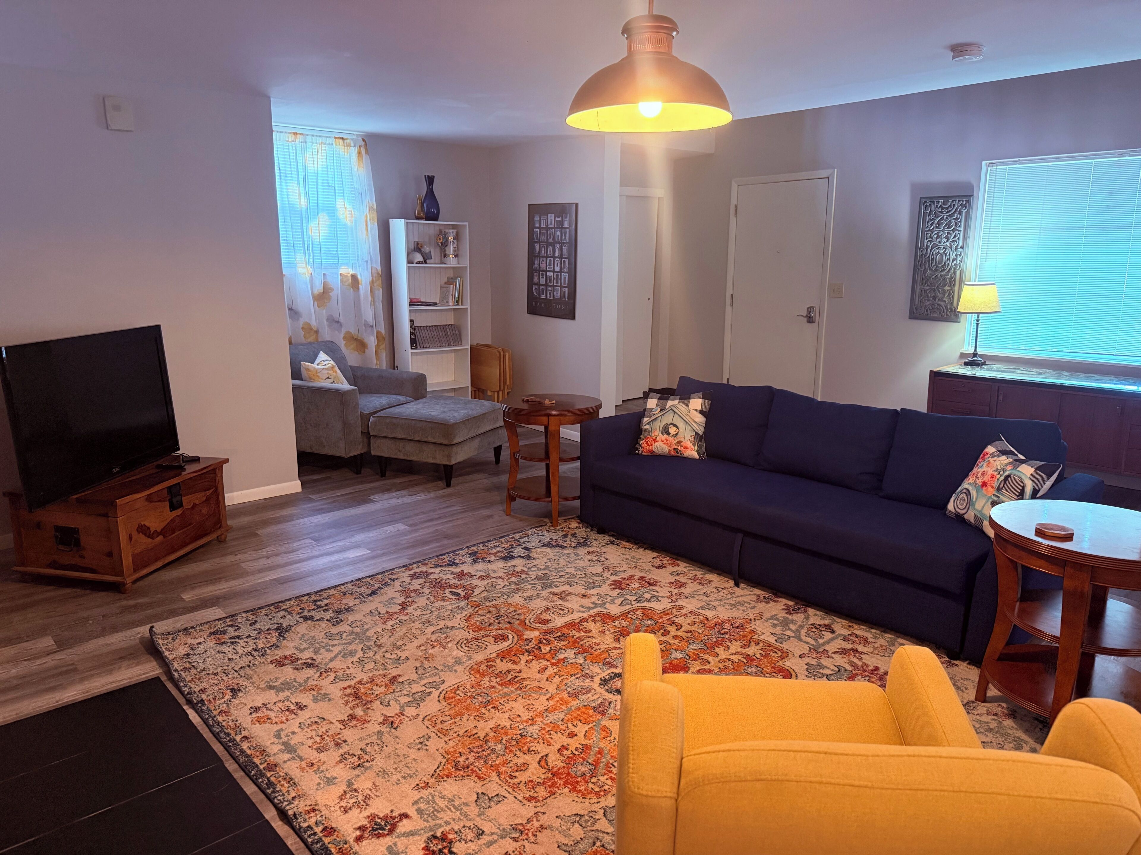 Una sala de estar con sofá, sillón, televisor y alfombra decorativa.