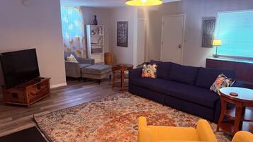 Una sala de estar con sofá, sillón, televisor y alfombra decorativa.