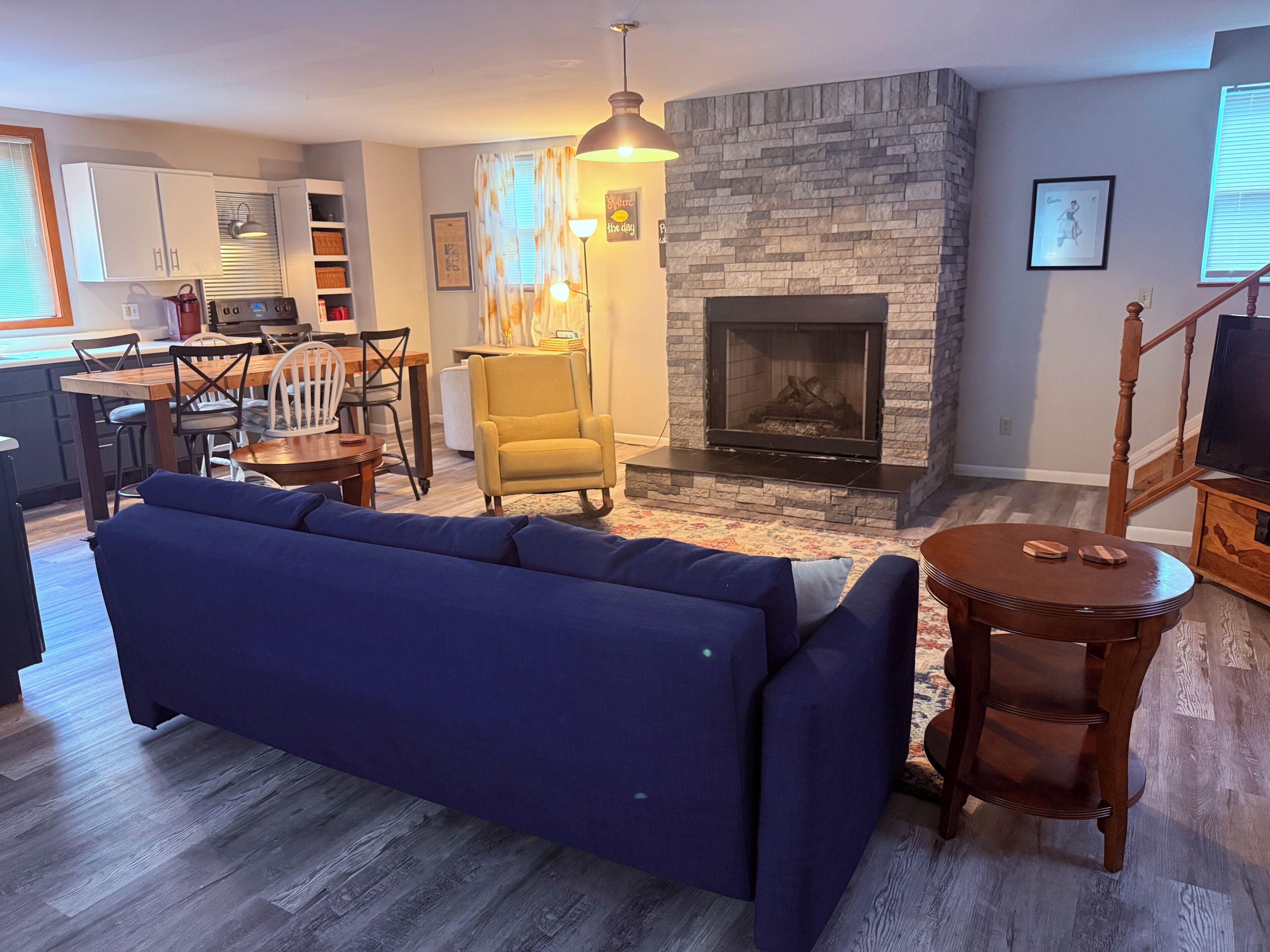 Ein Wohnzimmer mit einer Couch, einem Kamin, einem Essbereich und einer Küche.