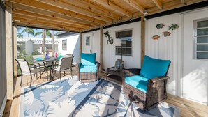 Un patio al aire libre con mobiliario de mimbre, una mesa y sillas.