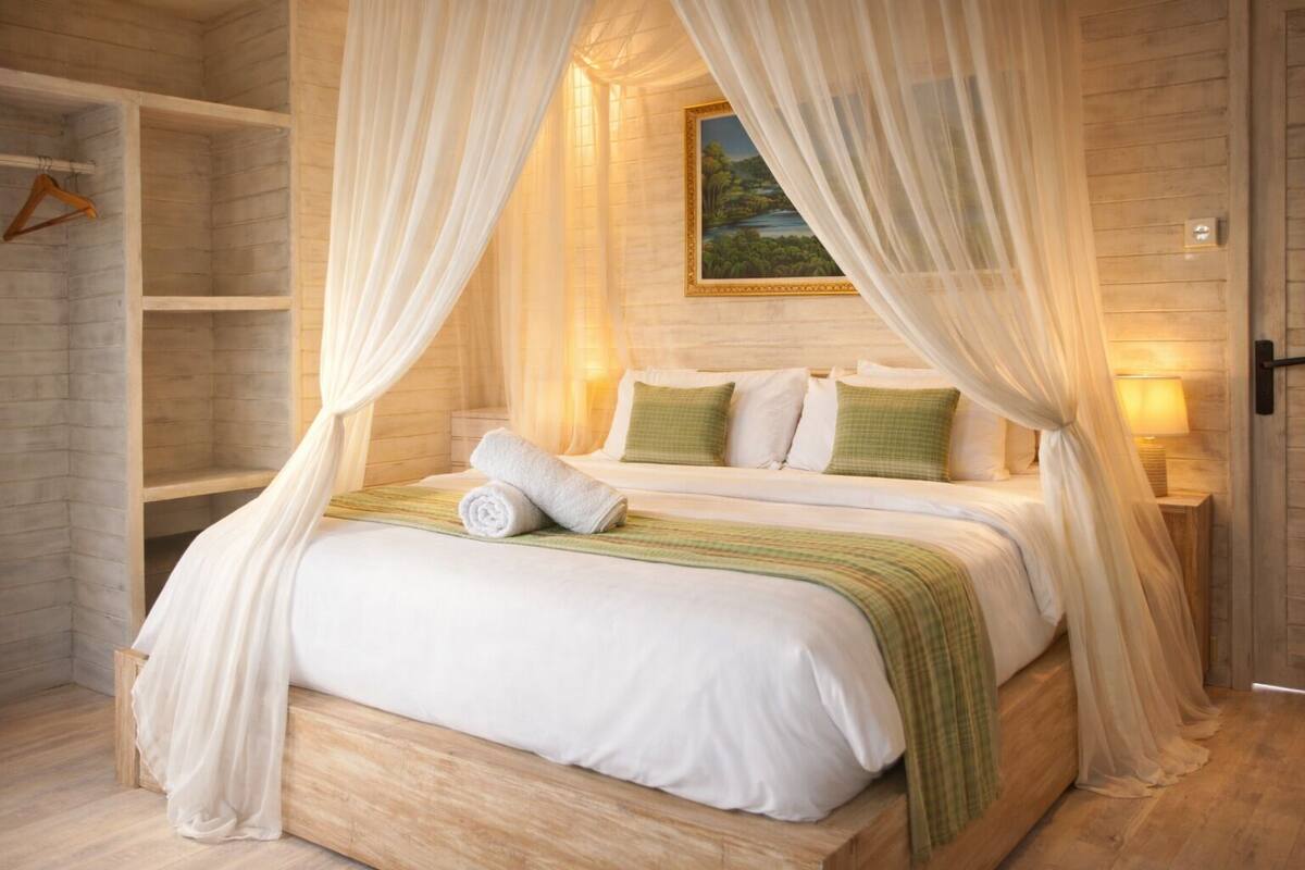 Une chambre à coucher avec un lit à baldaquin, une tête de lit en bois et un tableau au mur.