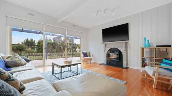 A spacious living room with a large TV, comfortable seating, and a fireplace.