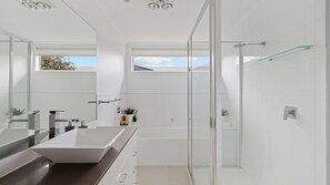 A modern bathroom with a large rectangular sink, a glass shower enclosure, and a large mirror.