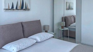 A bedroom with a bed, two bedside lamps, and a wall with sailboat paintings. - Lovely apartment in La Turbie with house sea view (La Turbie)