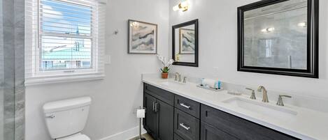 A modern bathroom with a toilet, dark wooden cabinets, a white sink, and framed artwork on the wall.