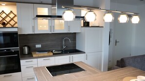 A modern kitchen with white cabinetry, a black stove, and a wooden island.