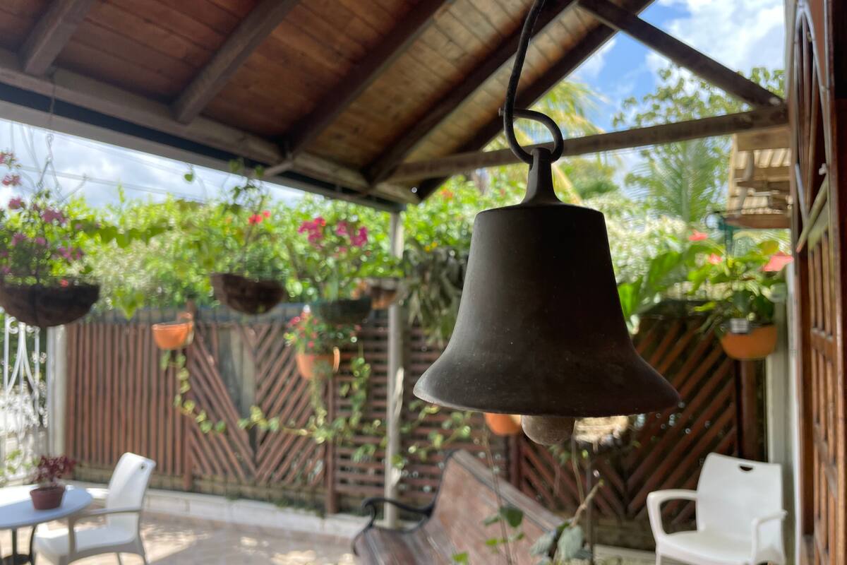 Un patio couvert agrémenté de jardinières suspendues et d’une table avec des chaises.