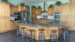 Une cuisine moderne avec des meubles en bois, des appareils en acier inoxydable et un îlot central doté de tabourets de bar.