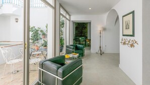 A modern living room with a green sofa, a dining area with a table and chairs, and a large window overlooking a balcony with potted plants. - Awesome home in Carmona (Carmona)