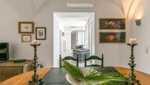 A dining area with a wooden table, two candle holders with lit candles, a bowl with green foliage, and framed artwork on the walls. - Awesome home in Carmona (Carmona)