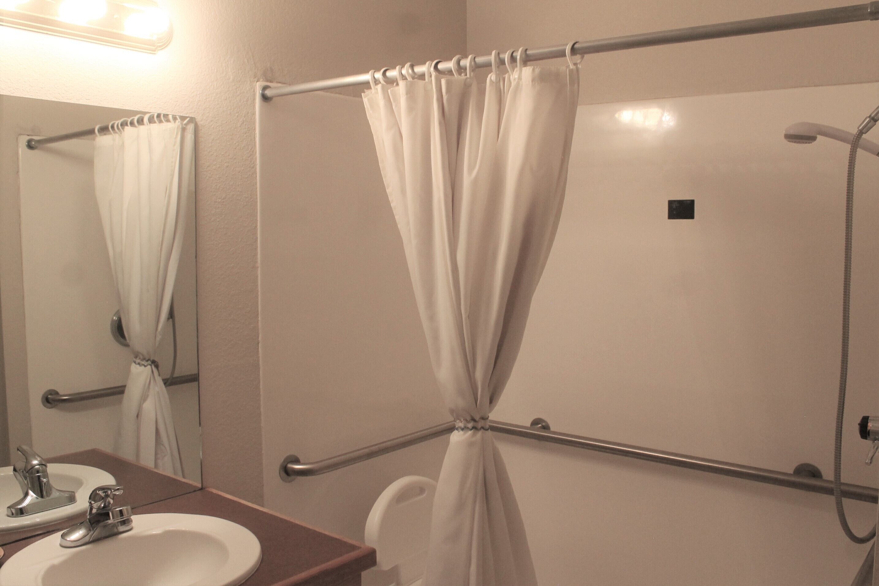 A bathroom with a white sink, mirror, and shower curtain.